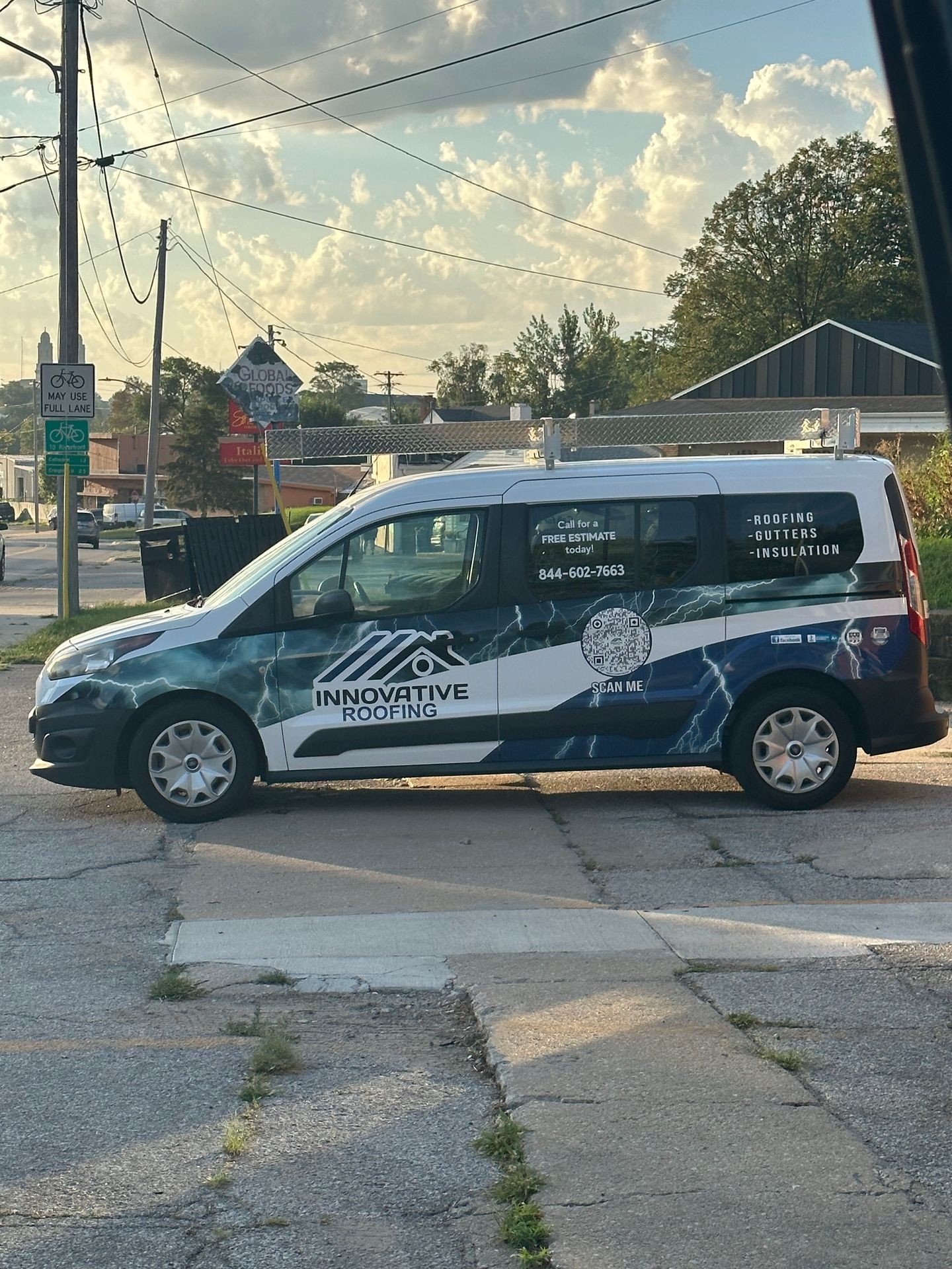 Innovative Roofing van parked on a street with signage for roofing services and free estimates.